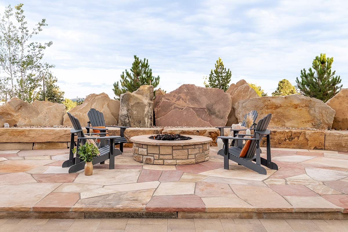 Custom stone firepit on a stone patio with surrounding boulders in Colorado.